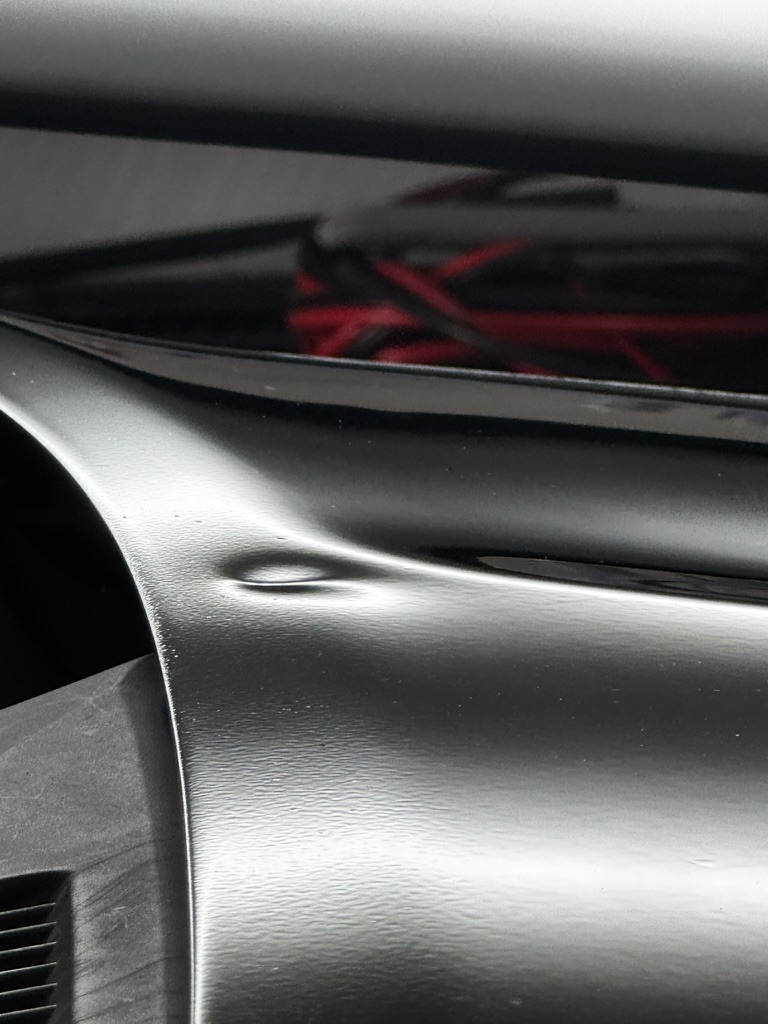 Rounded dent near a dark vehicle panel edge