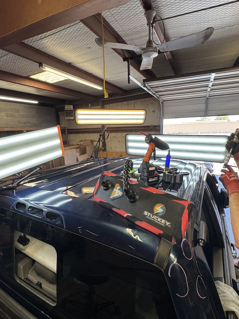 Hail-damaged roof set up for paintless dent repair under multiple lights