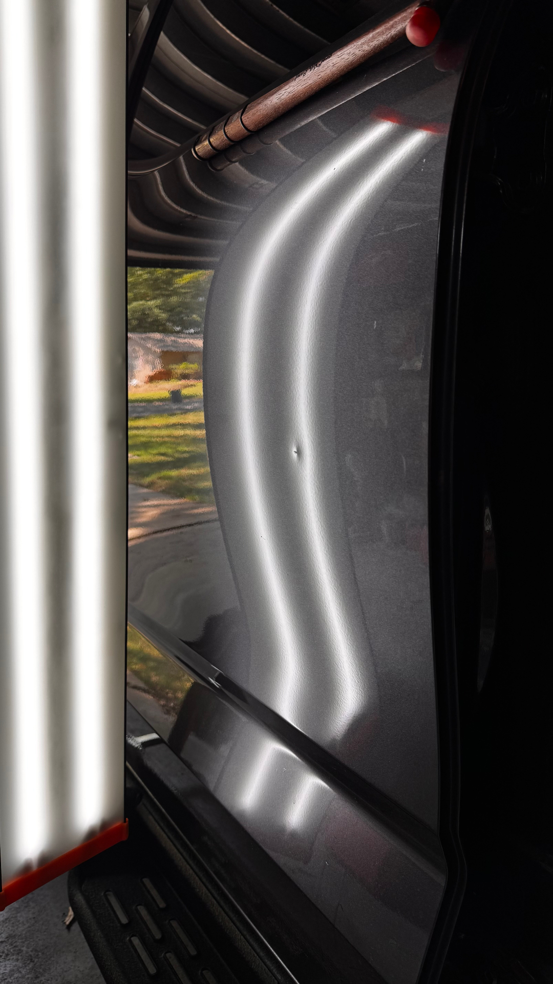 Small door dent inspected beneath a PDR reflection light