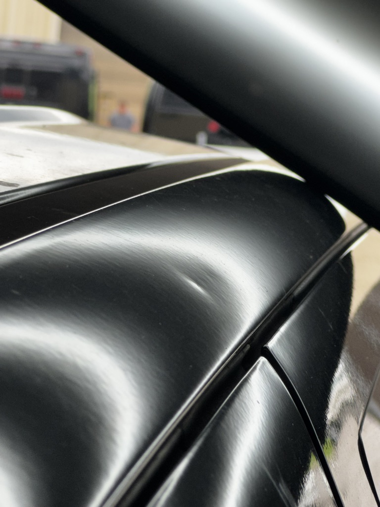 Minor dent near a roof rail under workshop lighting