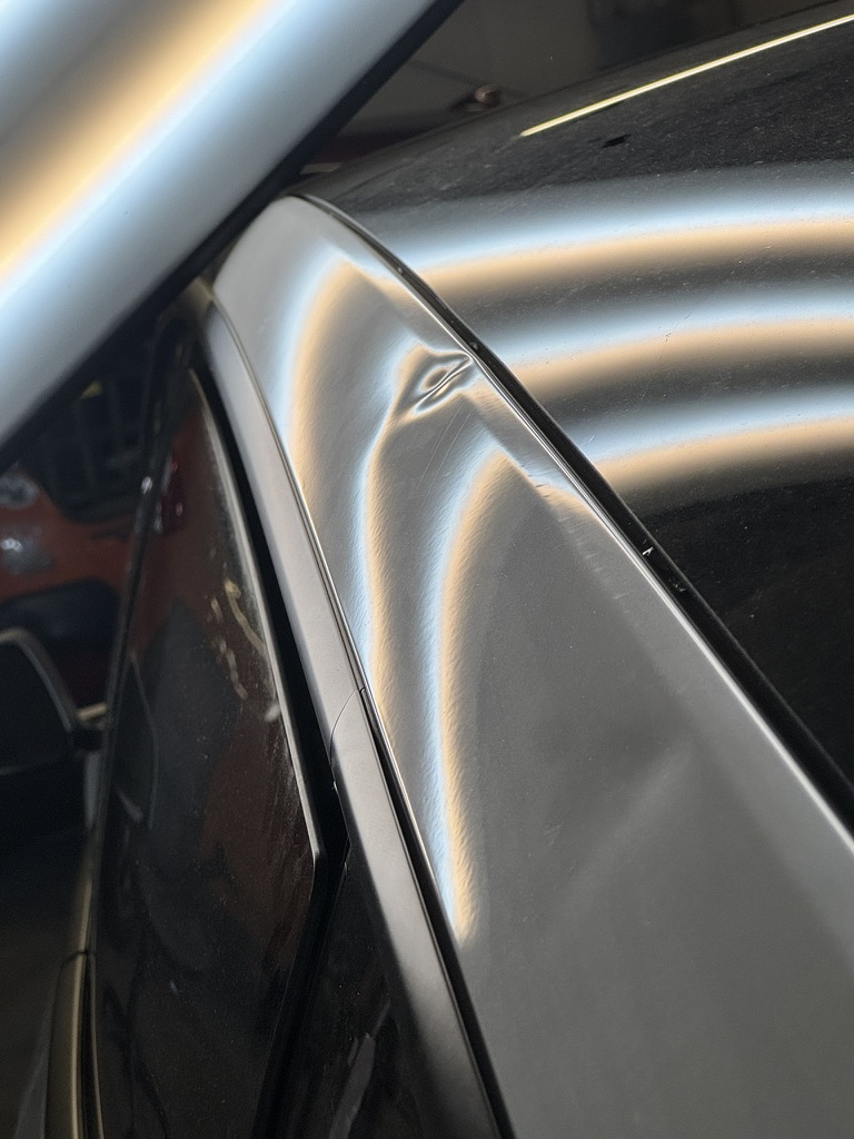 Sharp dent along a silver roof rail under PDR inspection lighting