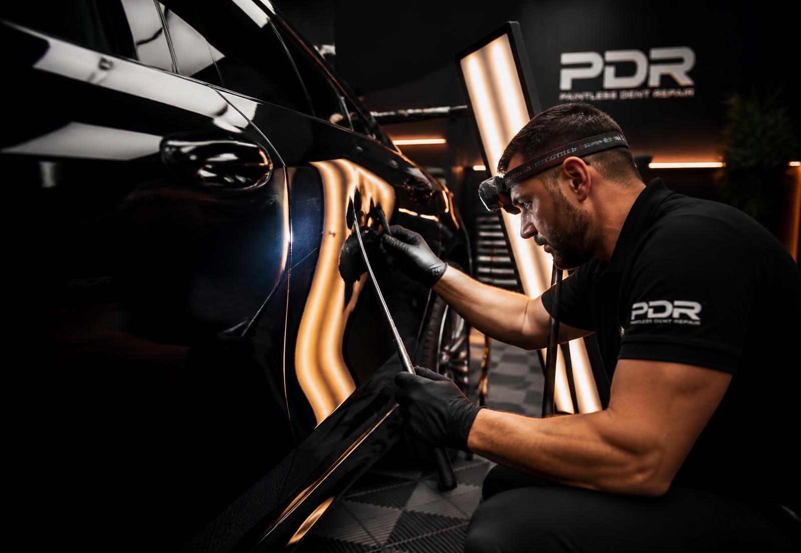Certified PDR technician removing a dent from a vehicle panel without paint